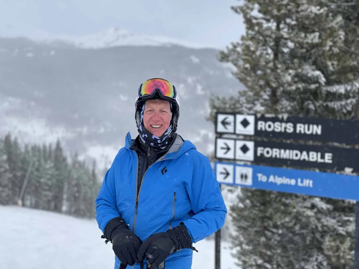 Larry Luke in ski gear beside a trail sign